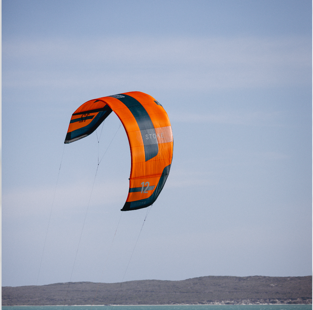 Orange Flysurfer  kite against a clear sky with a distant landscape.