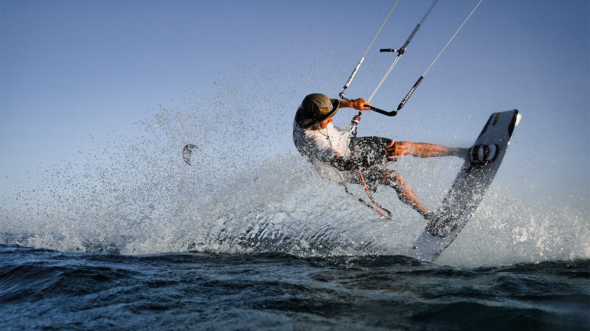 Kitesurfer carving hard through the water and throwing up a wall of spray